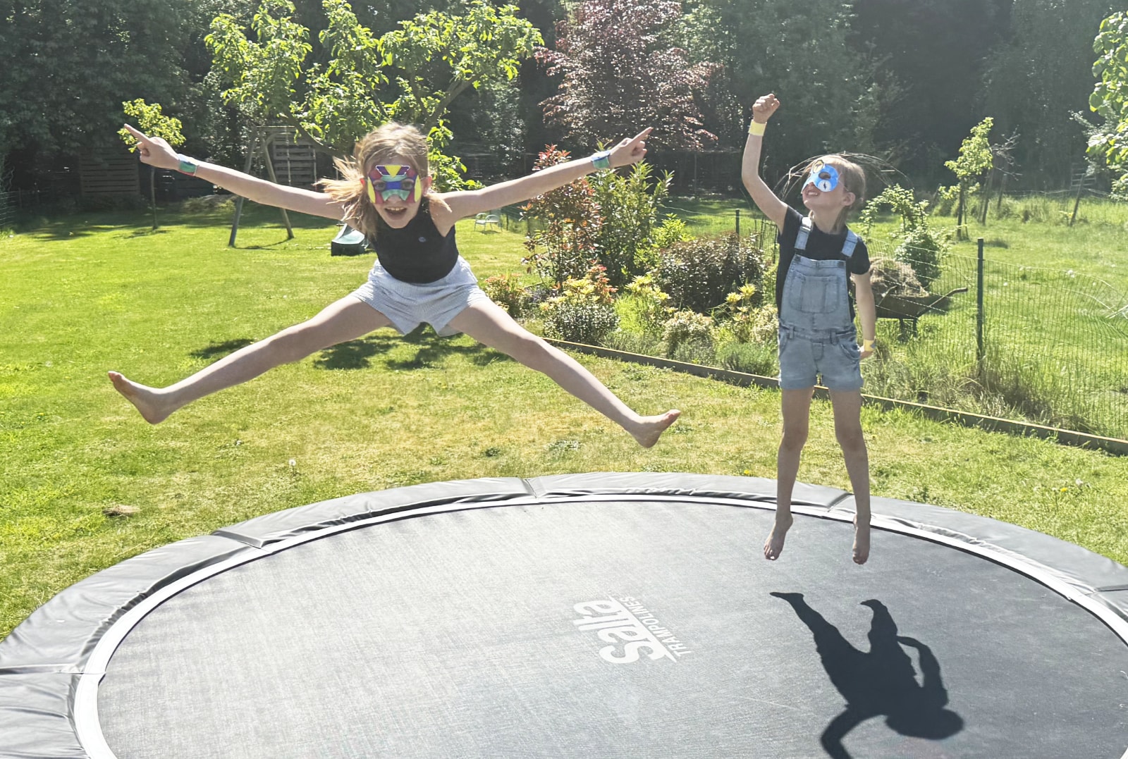 Kinderen verkleed als superhelden vliegen boven een trampoline.